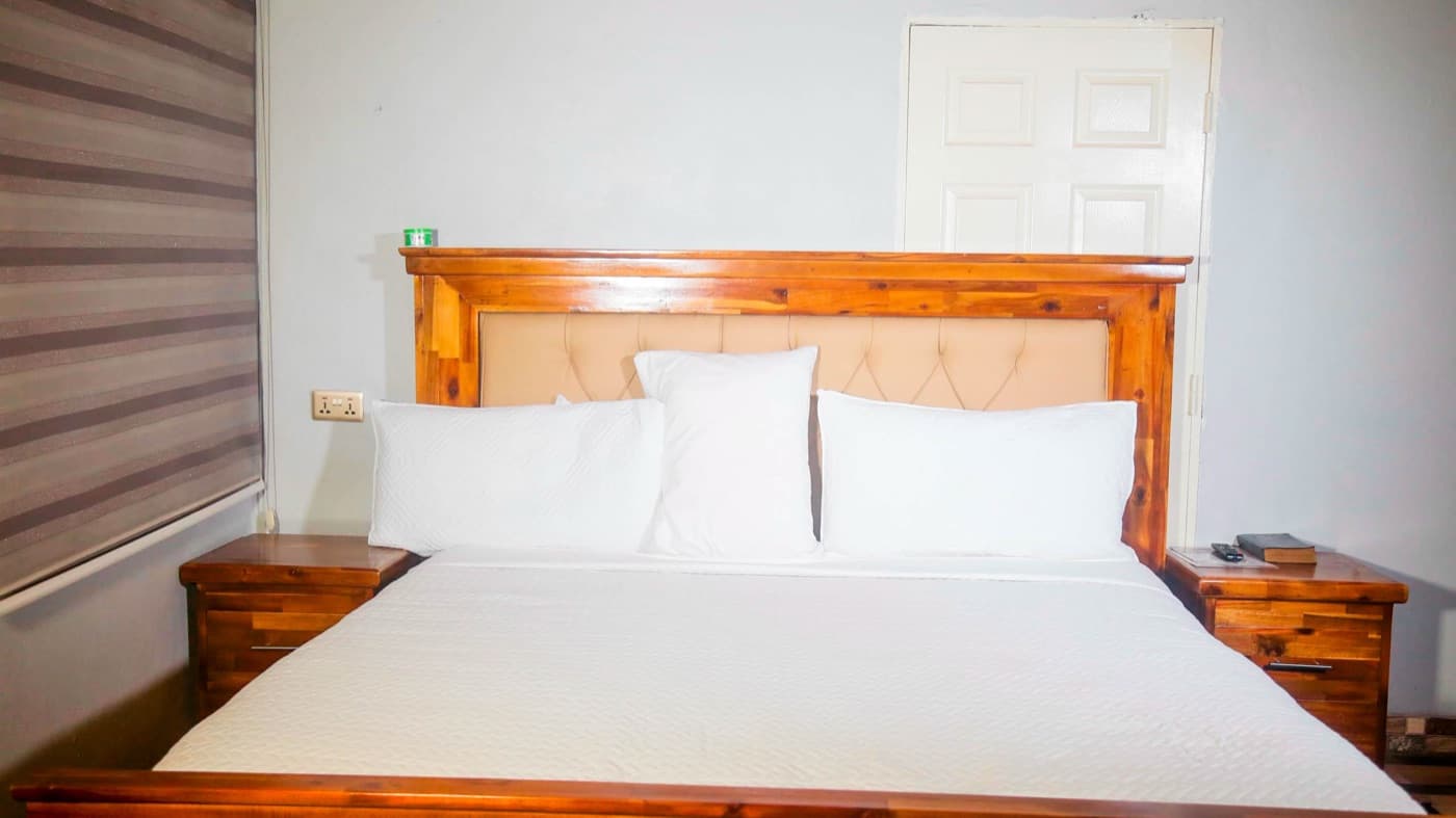 A double room with a wooden headboard and two nightstands at JC Guest House